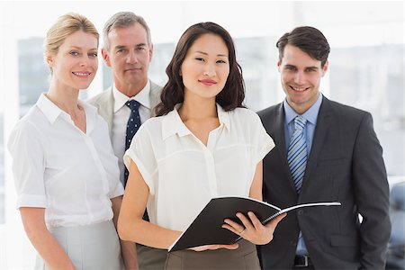 simsearch:400-07274497,k - Businesswoman holding document smiling at camera with her team in the office Stock Photo - Budget Royalty-Free & Subscription, Code: 400-07275324