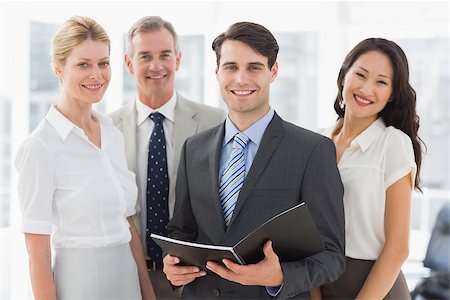 simsearch:400-07274497,k - Businessman holding document smiling at camera with his team in the office Stock Photo - Budget Royalty-Free & Subscription, Code: 400-07275323