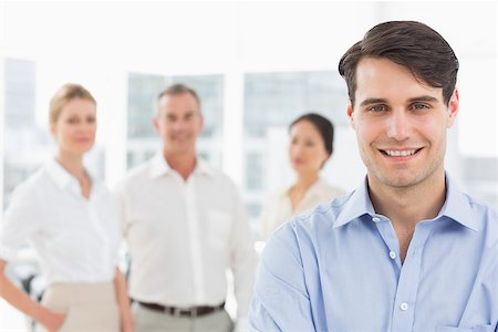 simsearch:400-07274497,k - Smiling businessman standing with team behind him in the office Stock Photo - Budget Royalty-Free & Subscription, Code: 400-07275368