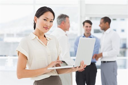 simsearch:400-07274497,k - Asian businesswoman using laptop with team behind her in the office Stock Photo - Budget Royalty-Free & Subscription, Code: 400-07275374