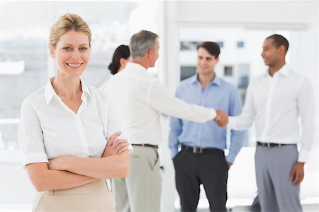 simsearch:400-07275394,k - Blonde businesswoman with team behind her smiling at camera in the office Stock Photo - Budget Royalty-Free & Subscription, Code: 400-07275378