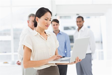 simsearch:400-07274497,k - Pretty asian businesswoman using laptop with team behind her in the office Stock Photo - Budget Royalty-Free & Subscription, Code: 400-07275372
