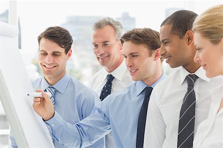 simsearch:400-07275394,k - Smiling colleagues watching young businessman write on whiteboard in the office Stock Photo - Budget Royalty-Free & Subscription, Code: 400-07275431