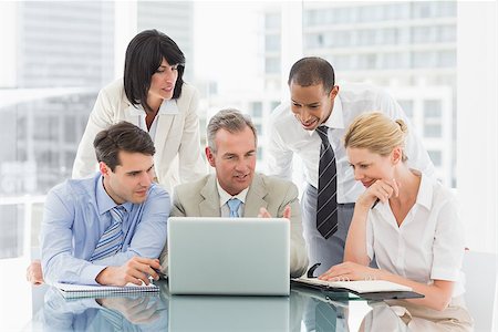 simsearch:400-07275394,k - Happy business people gathered around laptop looking at it in the office Stock Photo - Budget Royalty-Free & Subscription, Code: 400-07275456