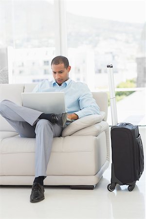 Businessman using laptop sitting on sofa waiting to depart on business trip in the office Stock Photo - Budget Royalty-Free & Subscription, Code: 400-07275546