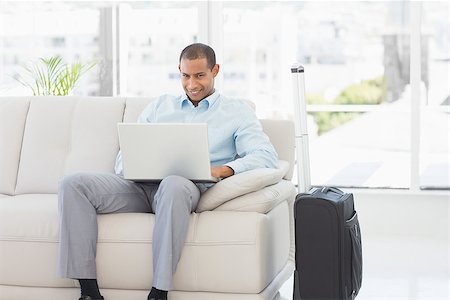 Happy businessman using laptop waiting to depart on business trip in the office Stock Photo - Budget Royalty-Free & Subscription, Code: 400-07275548