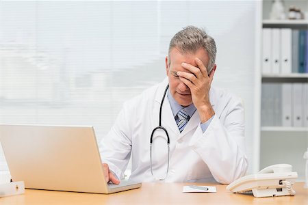 simsearch:614-06898452,k - Stressed doctor sitting at his desk in his office at the hospital Stock Photo - Budget Royalty-Free & Subscription, Code: 400-07275582