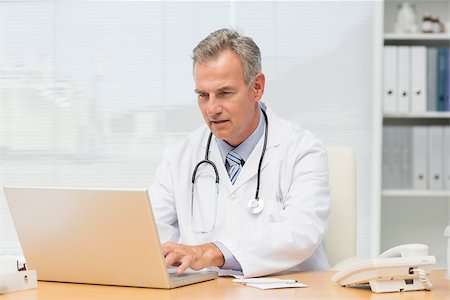 simsearch:614-06898452,k - Focused doctor sitting at his desk using his laptop in his office at the hospital Stock Photo - Budget Royalty-Free & Subscription, Code: 400-07275583