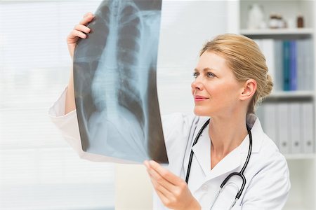 simsearch:400-07274751,k - Doctor examining an xray sitting at her desk in her office at the hospital Foto de stock - Super Valor sin royalties y Suscripción, Código: 400-07275598