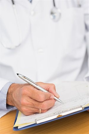 simsearch:614-06898452,k - Doctor sitting at his desk writing on clipboard in his office at the hospital Stock Photo - Budget Royalty-Free & Subscription, Code: 400-07275591