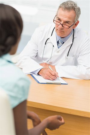 doctor with ethnic patient in office - Serious doctor listening to his patient and taking notes in his office at the hospital Stock Photo - Budget Royalty-Free & Subscription, Code: 400-07275625