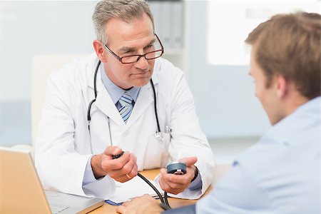 simsearch:400-07269643,k - Doctor taking his patients blood pressure in his office at the hospital Fotografie stock - Microstock e Abbonamento, Codice: 400-07275626