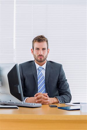 simsearch:400-07275251,k - Portrait of a serious young businessman with computer at office desk Stock Photo - Budget Royalty-Free & Subscription, Code: 400-07275662