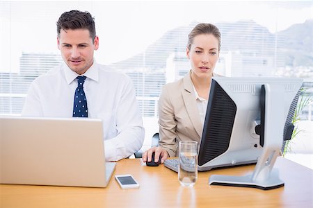 simsearch:400-05663929,k - Smartly dressed young man and woman using computer and laptop at office desk Stock Photo - Budget Royalty-Free & Subscription, Code: 400-07275764