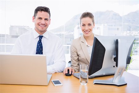 simsearch:400-05663929,k - Smartly dressed young man and woman using computer and laptop at office desk Stock Photo - Budget Royalty-Free & Subscription, Code: 400-07275765