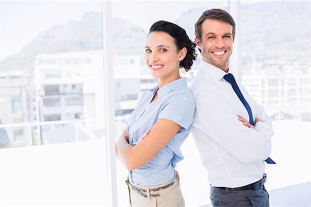 simsearch:400-07274414,k - Portrait of a smiling young business couple standing with arms crossed in a bright office Photographie de stock - Aubaine LD & Abonnement, Code: 400-07275828