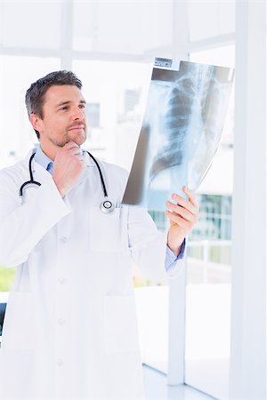 simsearch:400-07275966,k - Serious male doctor examining xray in the medical office Foto de stock - Super Valor sin royalties y Suscripción, Código: 400-07275963