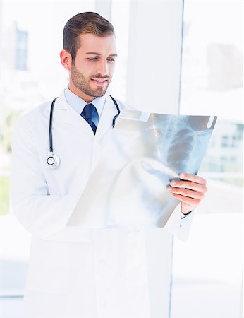 simsearch:400-07274751,k - Concentrated young male doctor examining xray in the medical office Foto de stock - Super Valor sin royalties y Suscripción, Código: 400-07275975