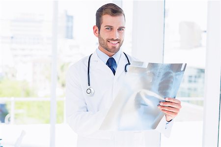 simsearch:400-07275966,k - Portrait of a smiling young male doctor examining xray in the medical office Foto de stock - Super Valor sin royalties y Suscripción, Código: 400-07275973