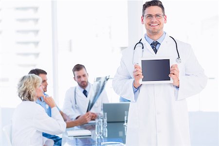 Doctor holding digital tablet with colleagues in meeting at a medical office Stock Photo - Budget Royalty-Free & Subscription, Code: 400-07276017