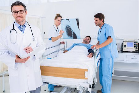 Doctors holding reports by patient in bed at the hospital Stock Photo - Budget Royalty-Free & Subscription, Code: 400-07276083