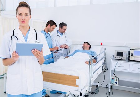 photo of patient in hospital in usa - Female doctor using digital tablet with colleagues and patient behind in the hospital Stock Photo - Budget Royalty-Free & Subscription, Code: 400-07276094