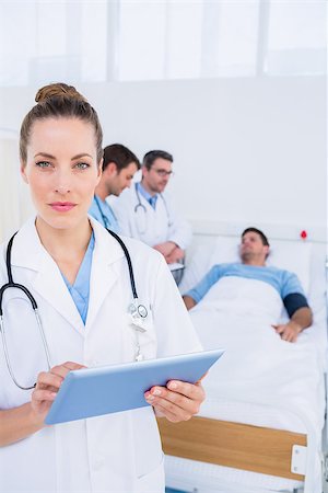 photo of patient in hospital in usa - Female doctor using digital tablet with colleagues and patient behind in the hospital Stock Photo - Budget Royalty-Free & Subscription, Code: 400-07276098