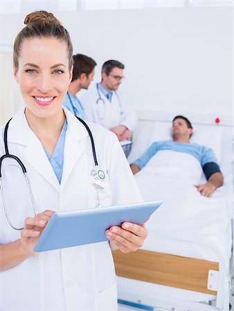 Female doctor using digital tablet with colleagues and patient behind in the hospital Stock Photo - Budget Royalty-Free & Subscription, Code: 400-07276099