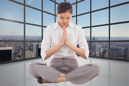 simsearch:400-07277816,k - Businesswoman sitting in lotus pose against room with large window showing city Fotografie stock - Microstock e Abbonamento, Codice: 400-07277529