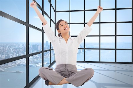 simsearch:400-07277816,k - Cheering businesswoman sitting cross legged against room with large window showing city Fotografie stock - Microstock e Abbonamento, Codice: 400-07277583