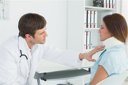 simsearch:400-07269643,k - Side view of a male doctor examining a patient's neck at desk in medical office Fotografie stock - Microstock e Abbonamento, Codice: 400-07270808