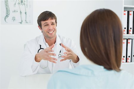 simsearch:400-07269643,k - Male doctor listening to patient with concentration at desk in medical office Fotografie stock - Microstock e Abbonamento, Codice: 400-07270802