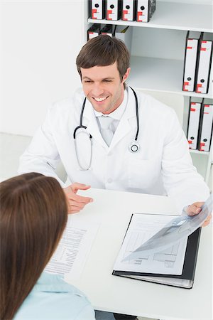 simsearch:400-07269643,k - Male doctor in conversation with female patient at desk in medical office Fotografie stock - Microstock e Abbonamento, Codice: 400-07270889