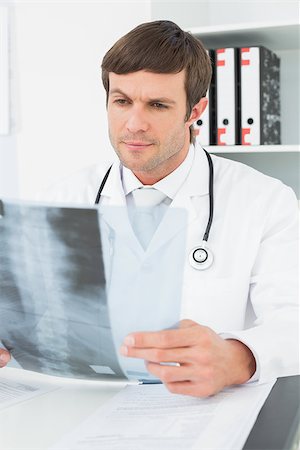 simsearch:400-07269250,k - Concentrated male doctor looking at x-ray picture of spine in the medical office Stock Photo - Budget Royalty-Free & Subscription, Code: 400-07270897