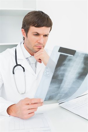 simsearch:400-07275966,k - Concentrated male doctor looking at x-ray picture of spine in the medical office Foto de stock - Super Valor sin royalties y Suscripción, Código: 400-07270906