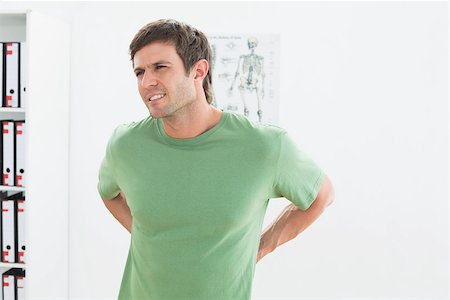 Portrait of a handsome young man with back pain standing in the medical office Stock Photo - Budget Royalty-Free & Subscription, Code: 400-07271083