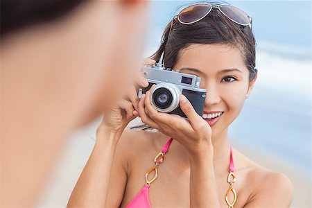 simsearch:400-08291180,k - A beautiful Asian Chinese girl or young woman wearing bikini at a beach looking happy taking pictures or photographs with a retro digital camera Foto de stock - Royalty-Free Super Valor e Assinatura, Número: 400-07272431