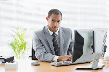 simsearch:400-07275251,k - Portrait of a serious young businessman using computer at office desk Stock Photo - Budget Royalty-Free & Subscription, Code: 400-07272679