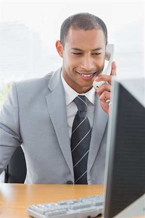 simsearch:400-07272682,k - Smiling young businessman using computer and phone at office desk Stockbilder - Microstock & Abonnement, Bildnummer: 400-07272691