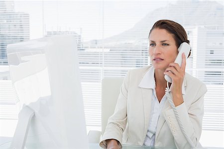 simsearch:400-07272682,k - Concentrated young businesswoman using computer and phone at office desk Stockbilder - Microstock & Abonnement, Bildnummer: 400-07272853