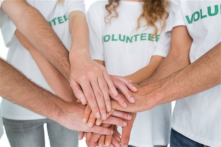 simsearch:400-07273307,k - Closeup mid section of volunteers with hands together over white background Stockbilder - Microstock & Abonnement, Bildnummer: 400-07273298