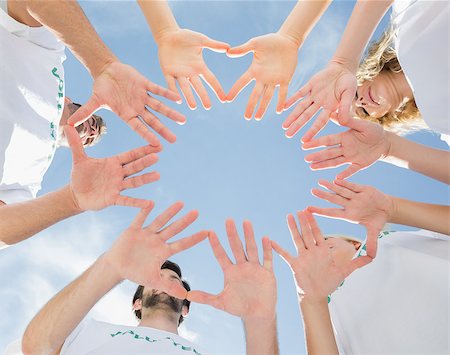 simsearch:400-07273325,k - Low angle view of volunteers with hands together against blue sky Foto de stock - Royalty-Free Super Valor e Assinatura, Número: 400-07273322