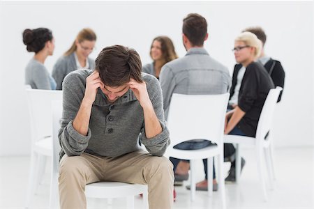 simsearch:400-07273405,k - Group therapy in session sitting in a circle with therapist while man in foreground Fotografie stock - Microstock e Abbonamento, Codice: 400-07273425