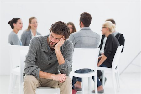 simsearch:400-07273405,k - Group therapy in session sitting in a circle with therapist while man in foreground Fotografie stock - Microstock e Abbonamento, Codice: 400-07273426