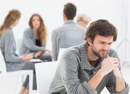 simsearch:400-07273405,k - Group therapy in session sitting in a circle with therapist while man in foreground Fotografie stock - Microstock e Abbonamento, Codice: 400-07273429