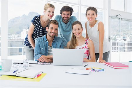 simsearch:400-07273325,k - Young casual business people using laptop together in a bright office Foto de stock - Royalty-Free Super Valor e Assinatura, Número: 400-07273474