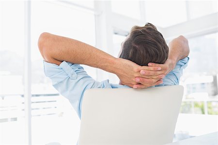 Rear view of a relaxed casual young man resting with hands behind head in a bright office Stock Photo - Budget Royalty-Free & Subscription, Code: 400-07273536