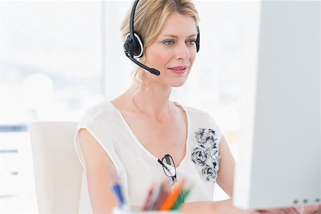Casual young woman with headset using computer in a bright office Stock Photo - Budget Royalty-Free & Subscription, Code: 400-07273537
