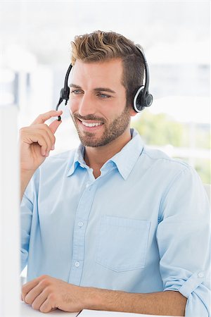 Closeup of a casual young man with headset using computer in a bright office Stock Photo - Budget Royalty-Free & Subscription, Code: 400-07273599