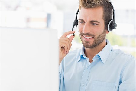 Closeup of a casual young man with headset using computer in a bright office Stock Photo - Budget Royalty-Free & Subscription, Code: 400-07273600